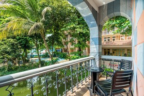 A balcony with a view of a pool and greenery, a table, and a chair. - Foy's Lake Resort (Chittagong)