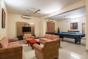 A modern living room with a pool table, sofas, a TV, and ceiling fans. - Foy's Lake Resort (Chittagong)