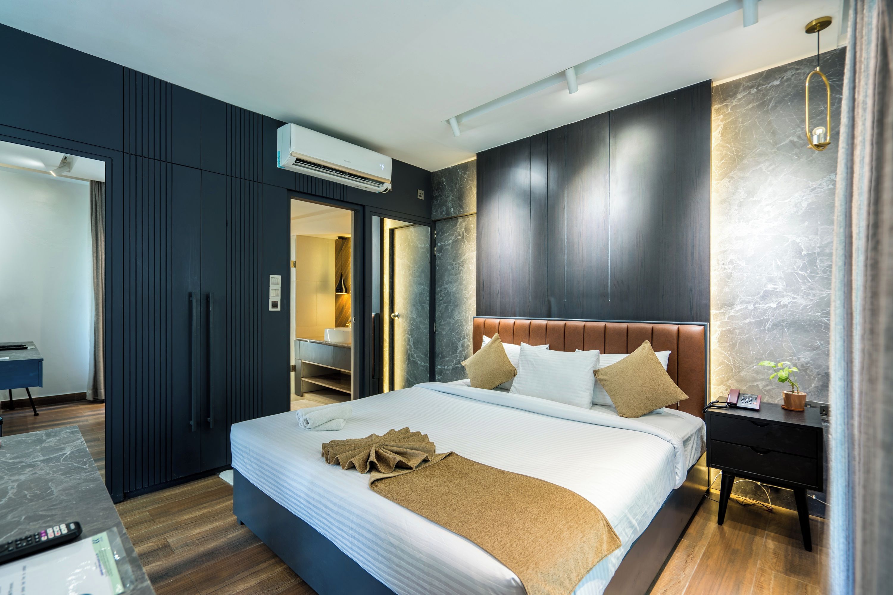 A modern hotel room with a large bed, a desk, and a bathroom visible through an open door.