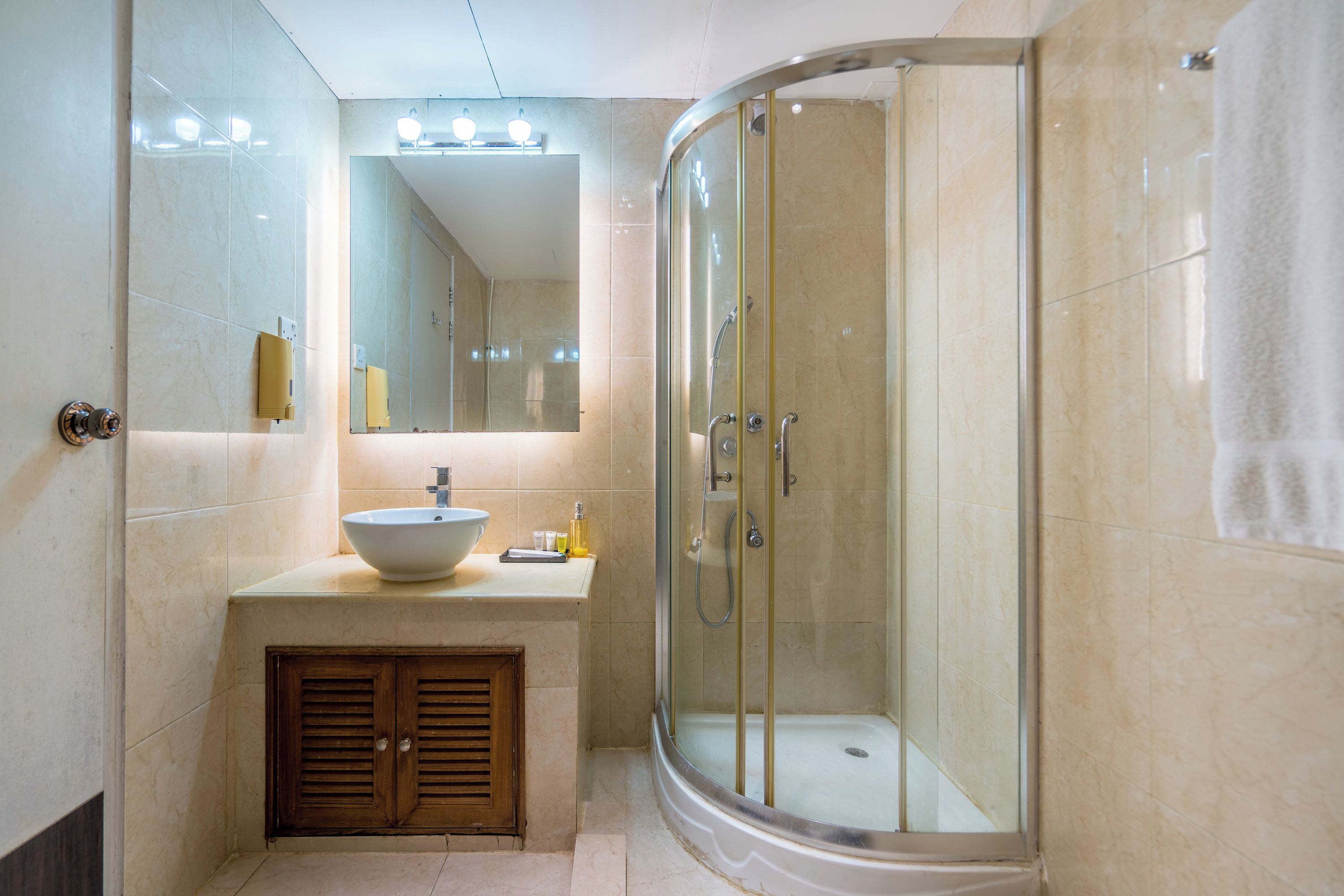 A modern bathroom with a glass-enclosed shower, a sink with a vessel basin, and a mirror above the vanity.