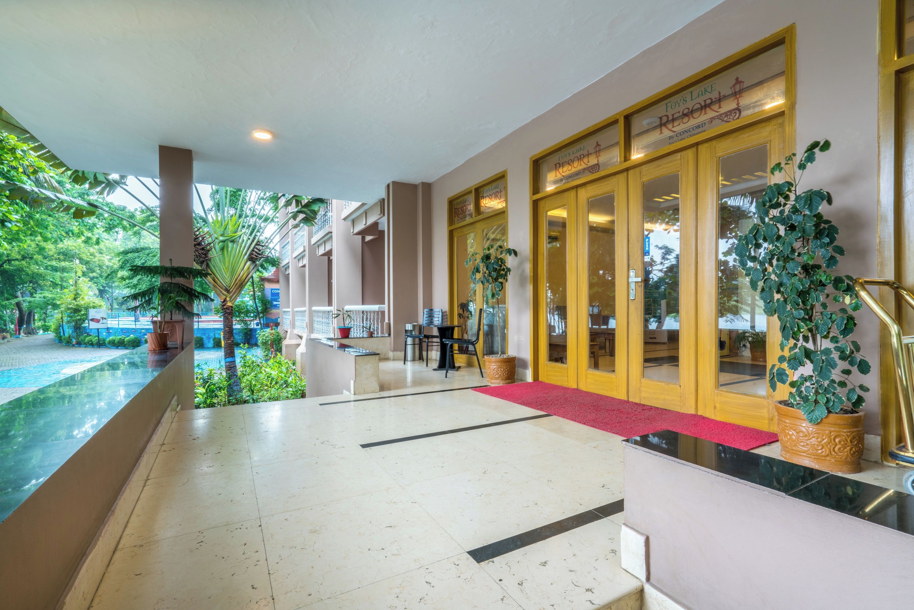 Un vestíbulo de hotel con una recepción, una alfombra roja y una entrada por puerta de cristal.