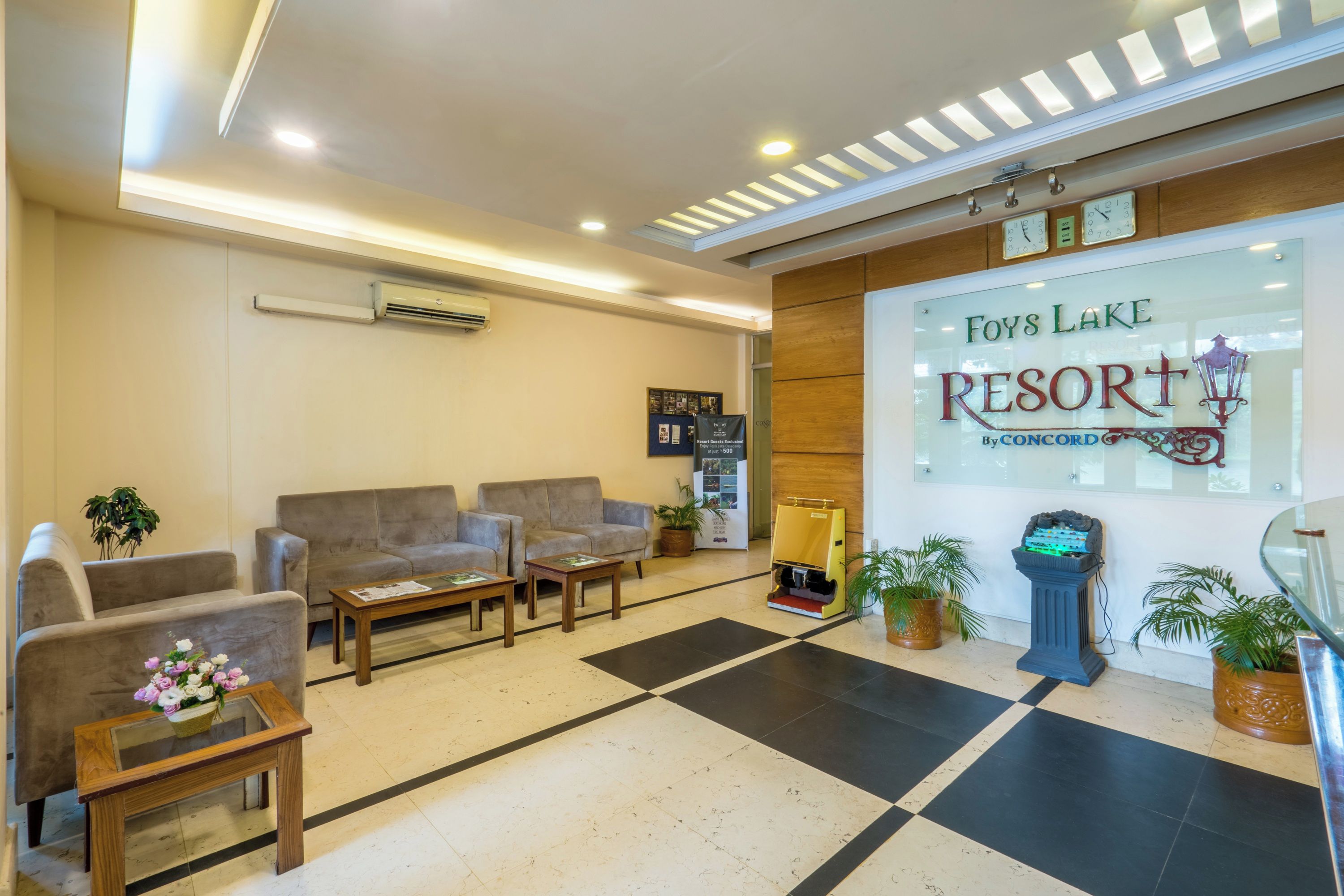A hotel lobby with a checkered floor, sofas, a reception desk, and a sign for Foys Lake Resort.
