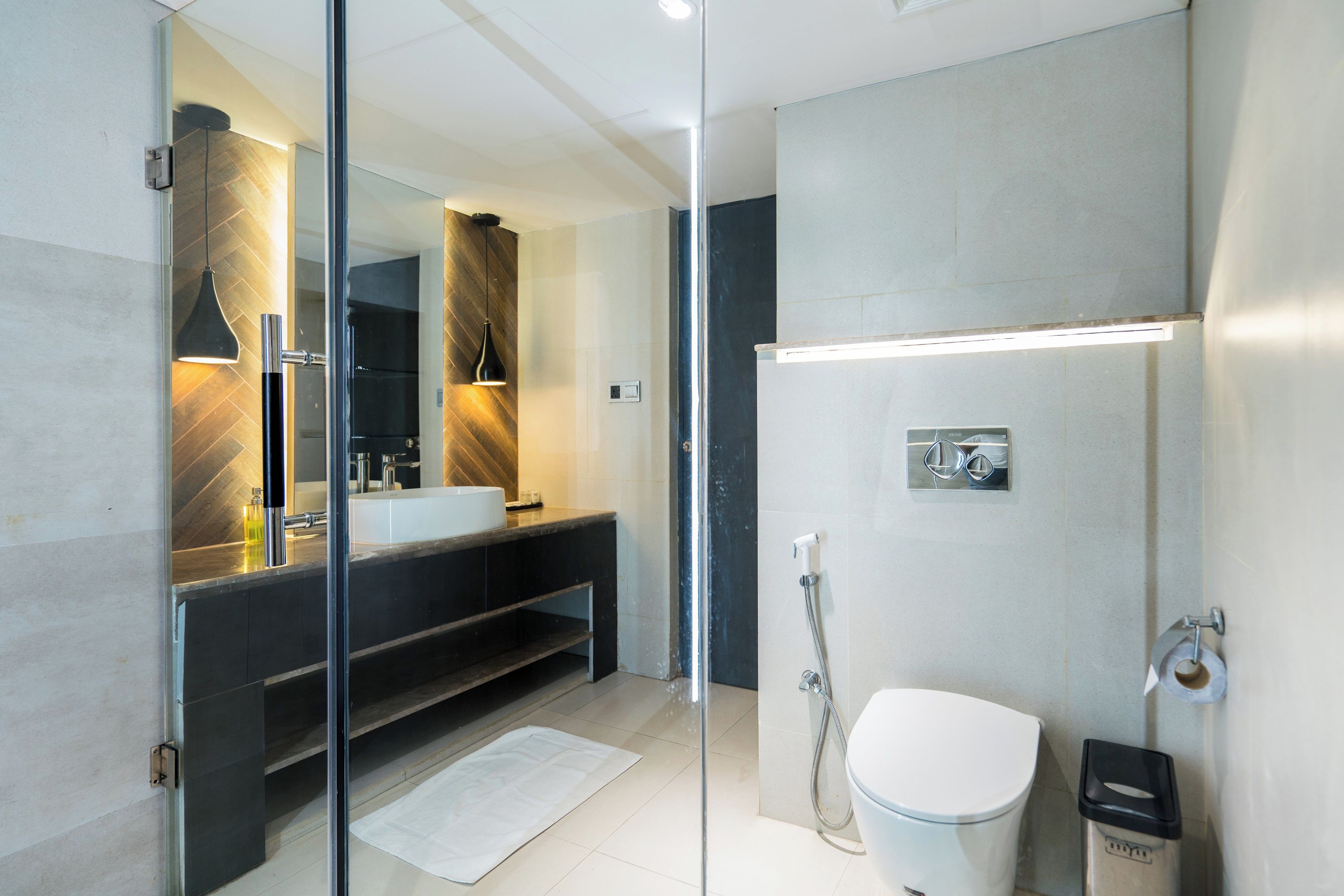 Un baño moderno con cabina de ducha de vidrio, inodoro blanco y tocador con espejo.