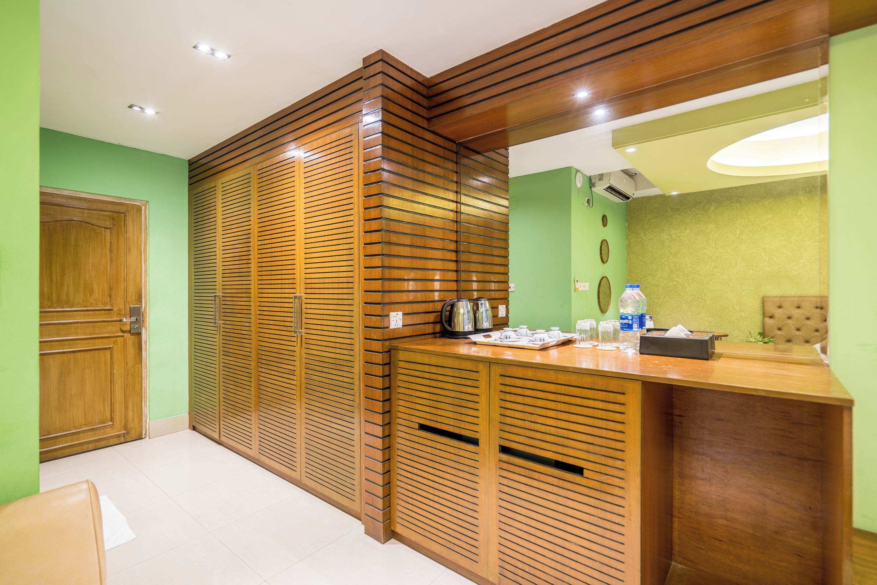A hotel room with a wooden partition, a reception desk, a green wall, and a bed.