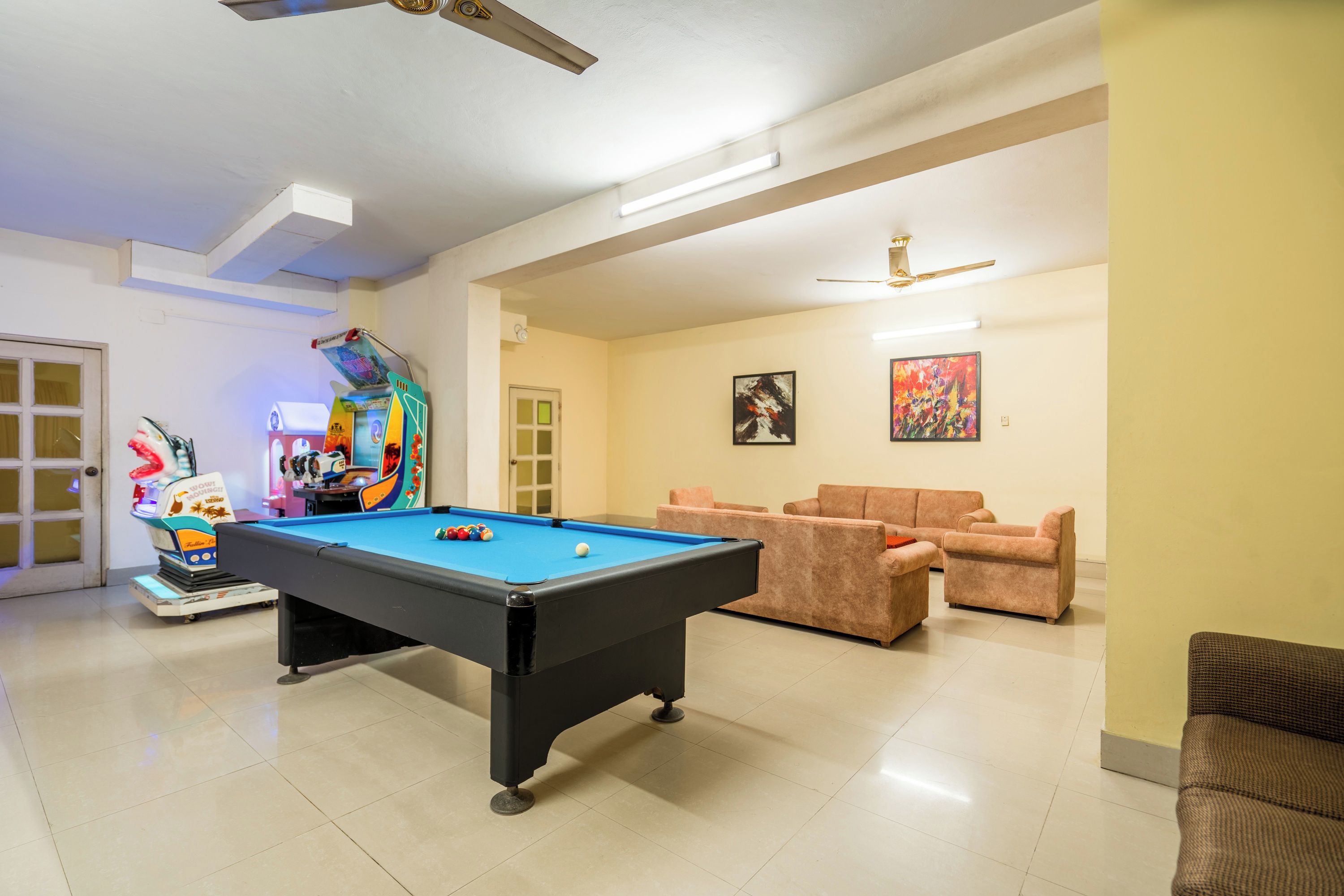 A pool table in a room with a ceiling fan, a door, and two sofas.