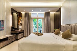 A modern hotel room with a large bed, a vanity with a mirror, a television, and a balcony with a view of greenery. - Foy's Lake Resort (Chittagong)