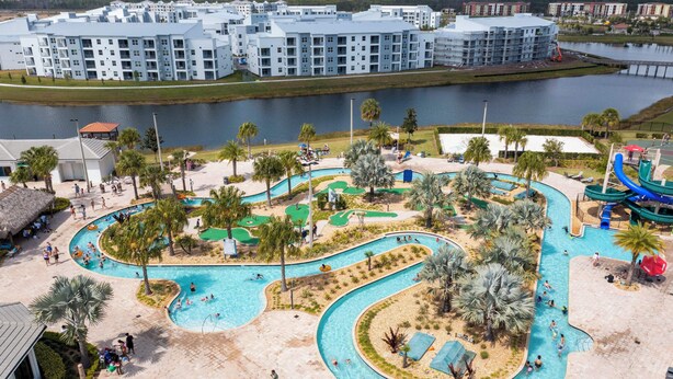 Een resort met een groot zwembad, palmbomen en uitzicht op een waterpartij.