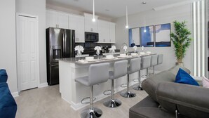 Een moderne keuken met een centraal eiland, barstoelen en een zithoek met een bank en fauteuils.