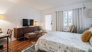 A bedroom with a bed, a television, a desk, and a chair.