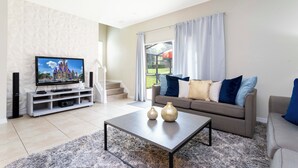 Ein Wohnzimmer mit Flachbildfernseher, Sofa, Couchtisch und dekorativen Vasen.