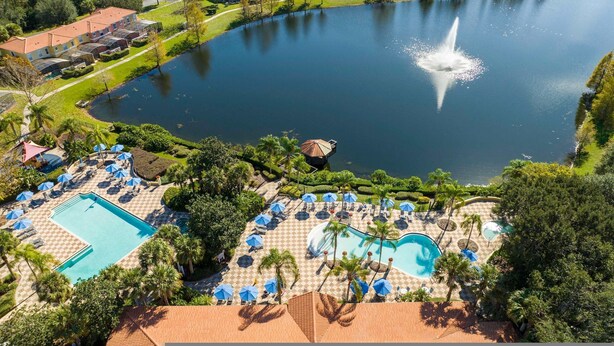 Ein Luftbild eines Resorts mit mehreren Swimmingpools, einer zentralen Fontäne und üppiger Bepflanzung.