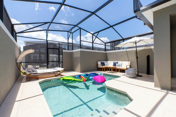 Une piscine intérieure avec des parois en verre transparent, des chaises longues et un bain de soleil.