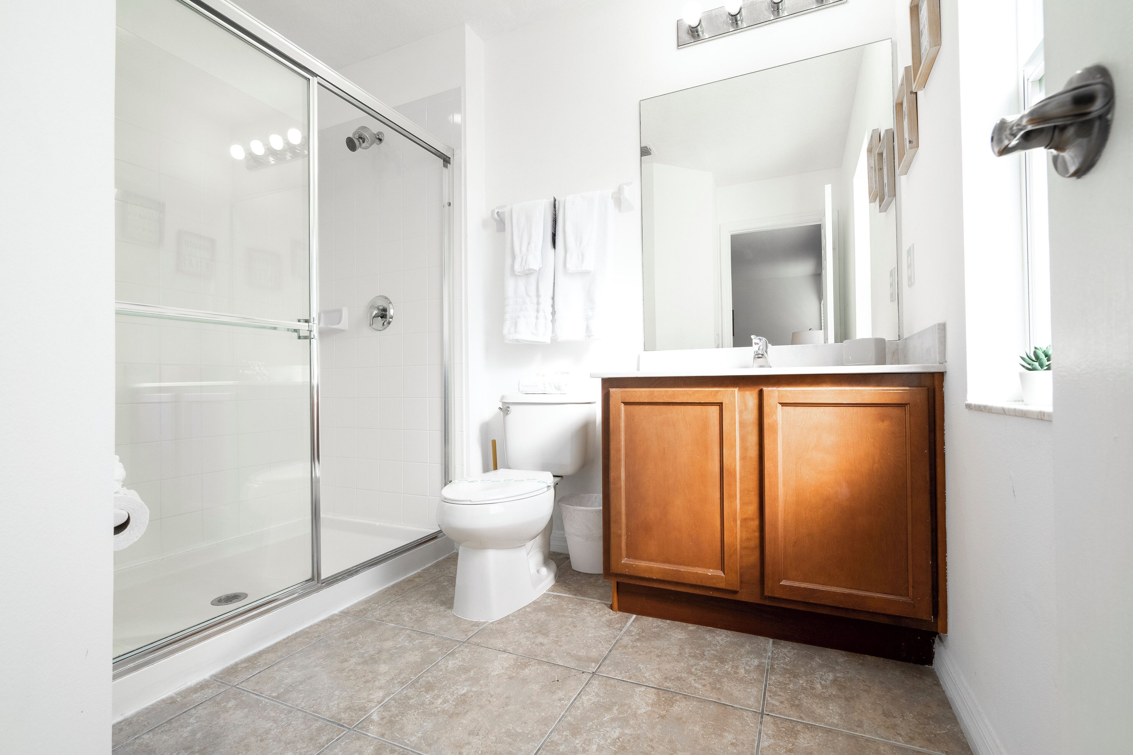 Un baño moderno con cabina de ducha de vidrio, inodoro blanco y muebles de madera.