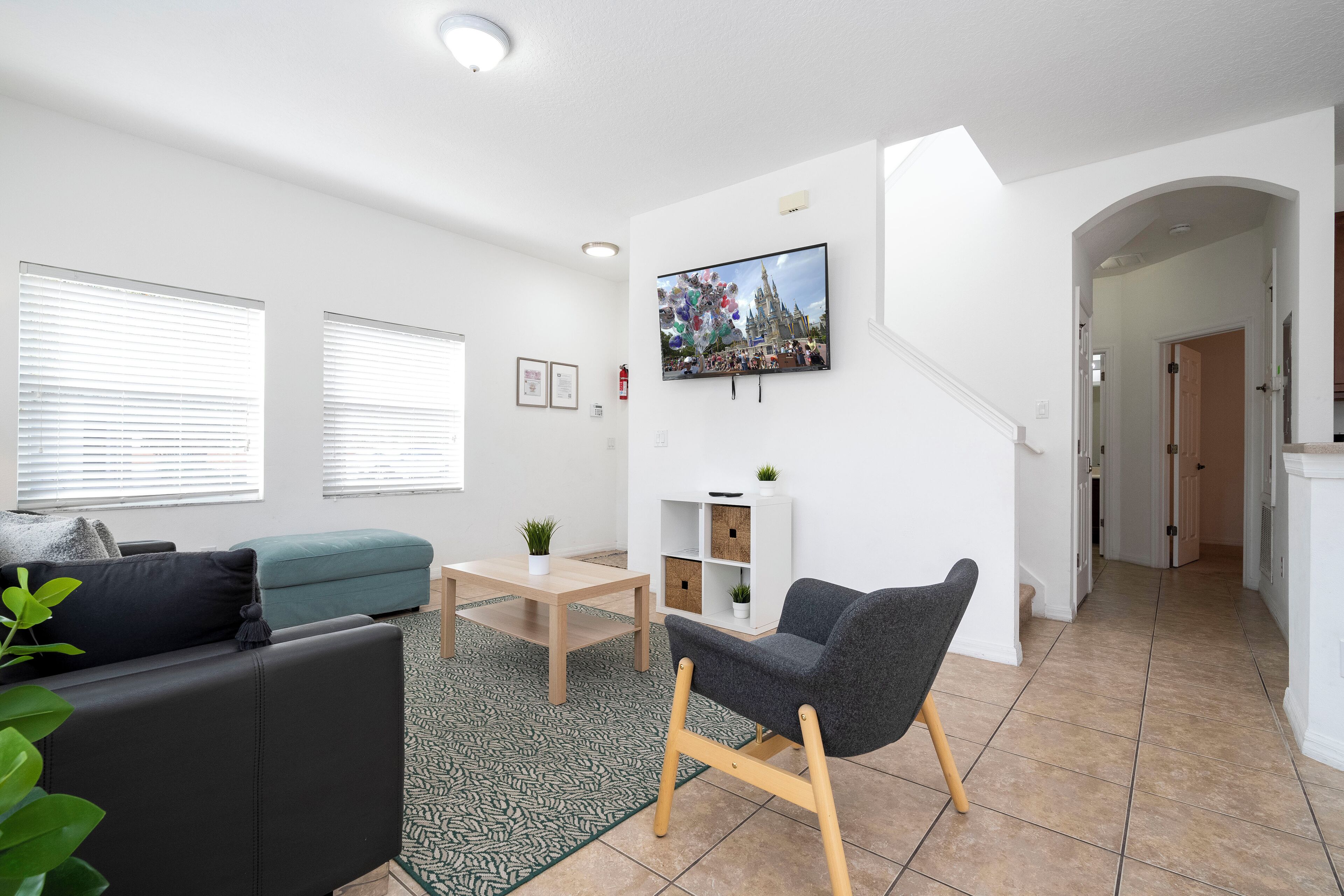 A modern living room with a sofa, a chair, a coffee table, and a TV mounted on the wall.