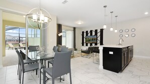 A modern kitchen with a dining area, featuring a glass table, black chairs, and pendant lighting. - Four Bedrooms w Pool Townhome 4841 (Kissimmee)