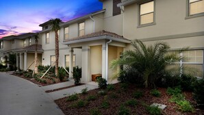 A row of townhouses with a landscaped front yard, including palm trees and shrubs. - Four Bedrooms w Pool Townhome 4841 (Kissimmee)
