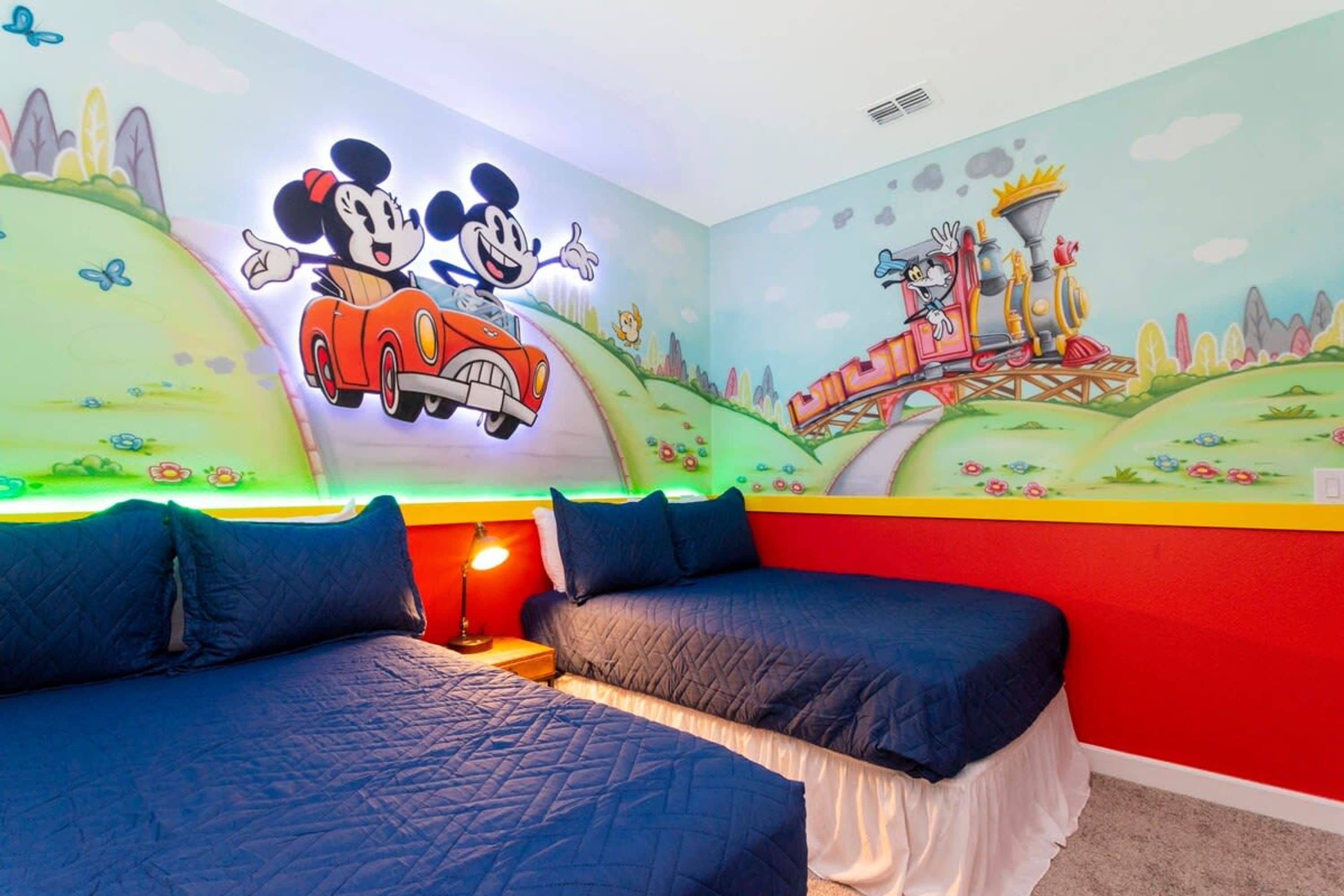 A children's room with Mickey and Minnie Mouse on the wall, a bed, and a nightstand.