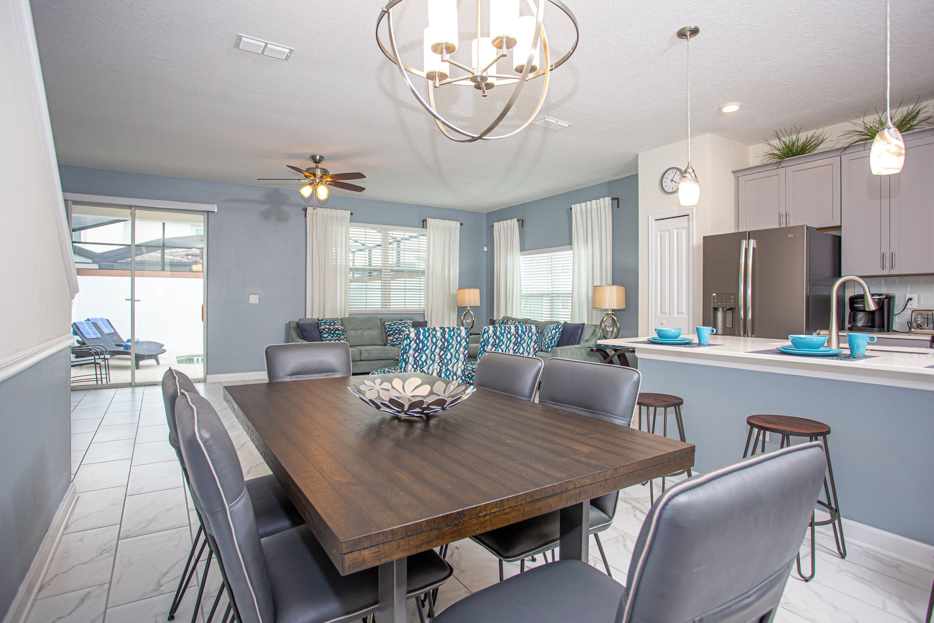 A modern kitchen with a refrigerator, stove, and dining area with a wooden table and chairs.