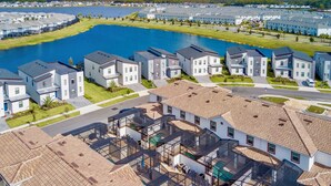 A residential area with modern houses, a central lake, and a swimming pool. - Wonderful 5 Bedroom w Pool Close to Disney 4801 (Kissimmee)