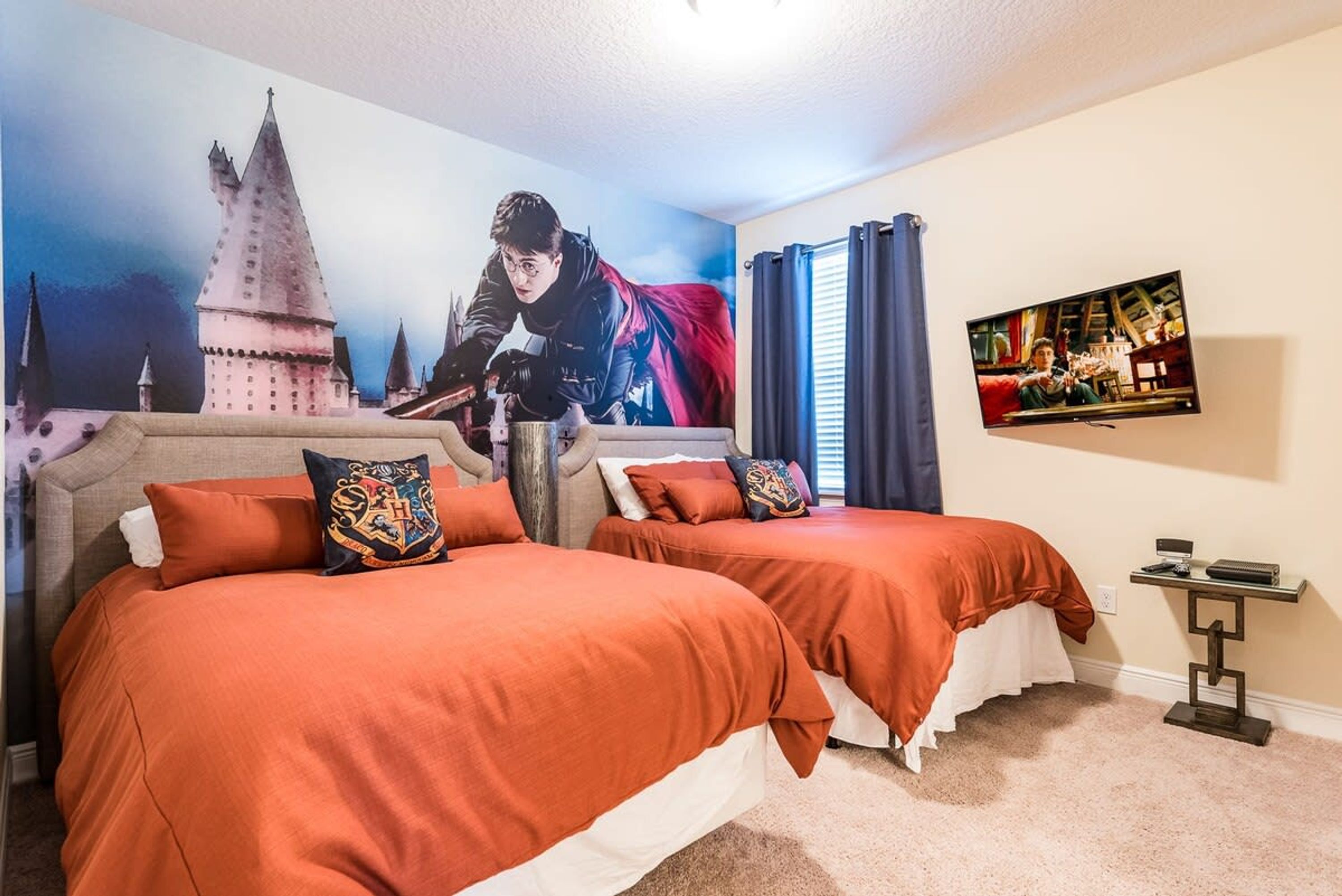 A bedroom with two beds, a large poster of a wizard, and a TV on the wall.