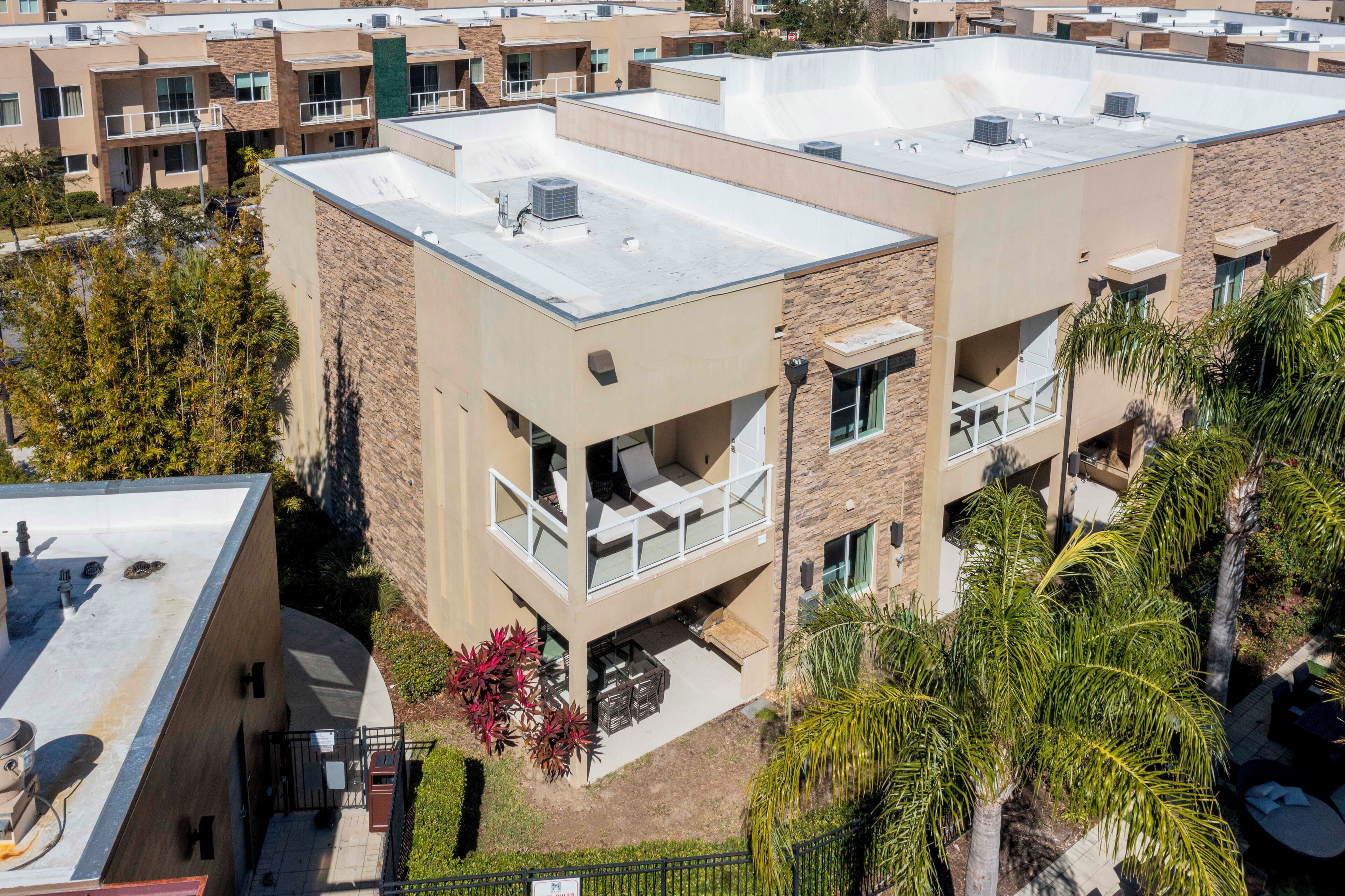 A multi-story building with a flat roof, outdoor seating area, and a visible garage.