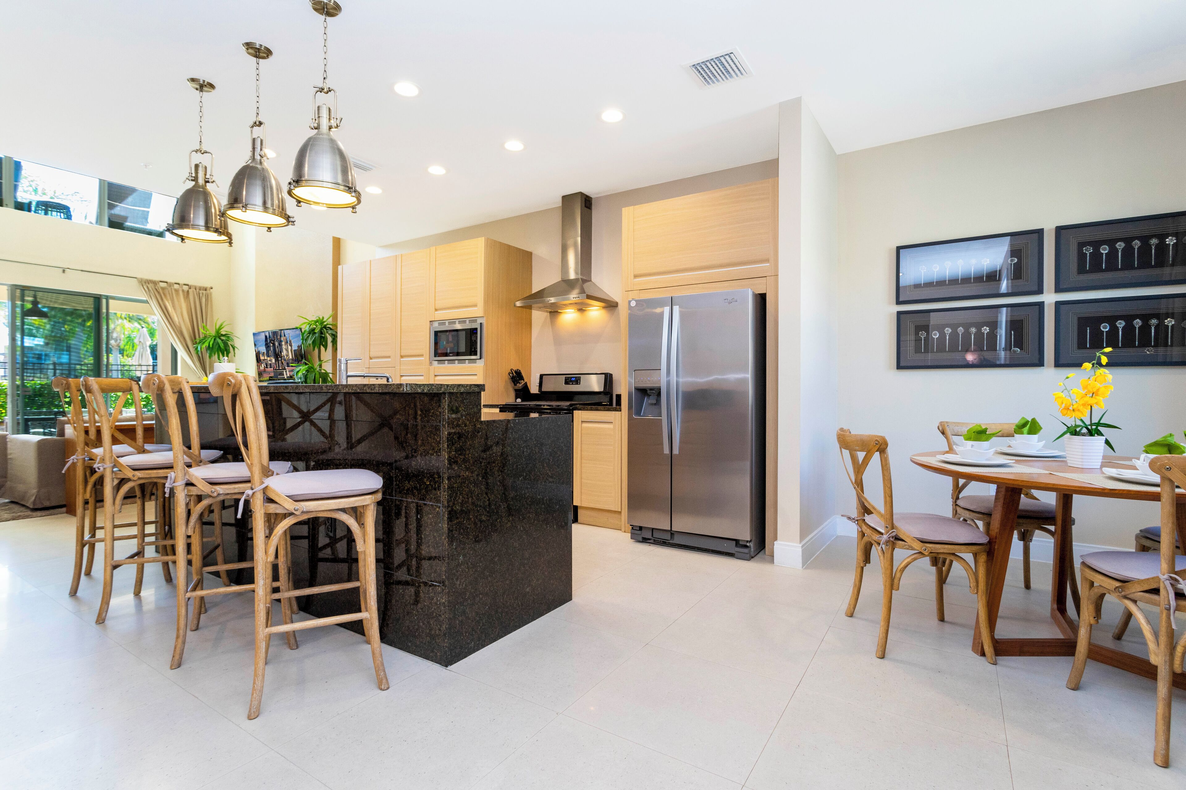 A modern kitchen with a central island, stainless steel appliances, and wooden chairs.
