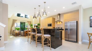 A modern kitchen with a central island, stainless steel appliances, and pendant lighting. - Marvelous 4 Bd Close to Disney Magic Village 3153 (Kissimmee)
