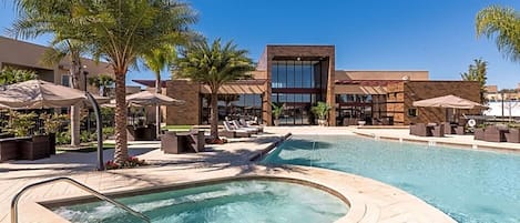 Un área de piscina con jacuzzi, sillas de descanso y palmeras.