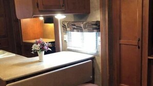 A compact kitchen with wooden cabinets, a countertop, and two stools. - Lake Fork bass fishing (Quitman)