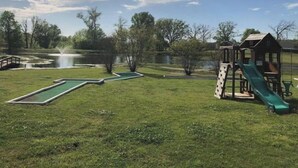A park with a pond, a small wooden playhouse, and a slide. - Lake Fork bass fishing (Quitman)