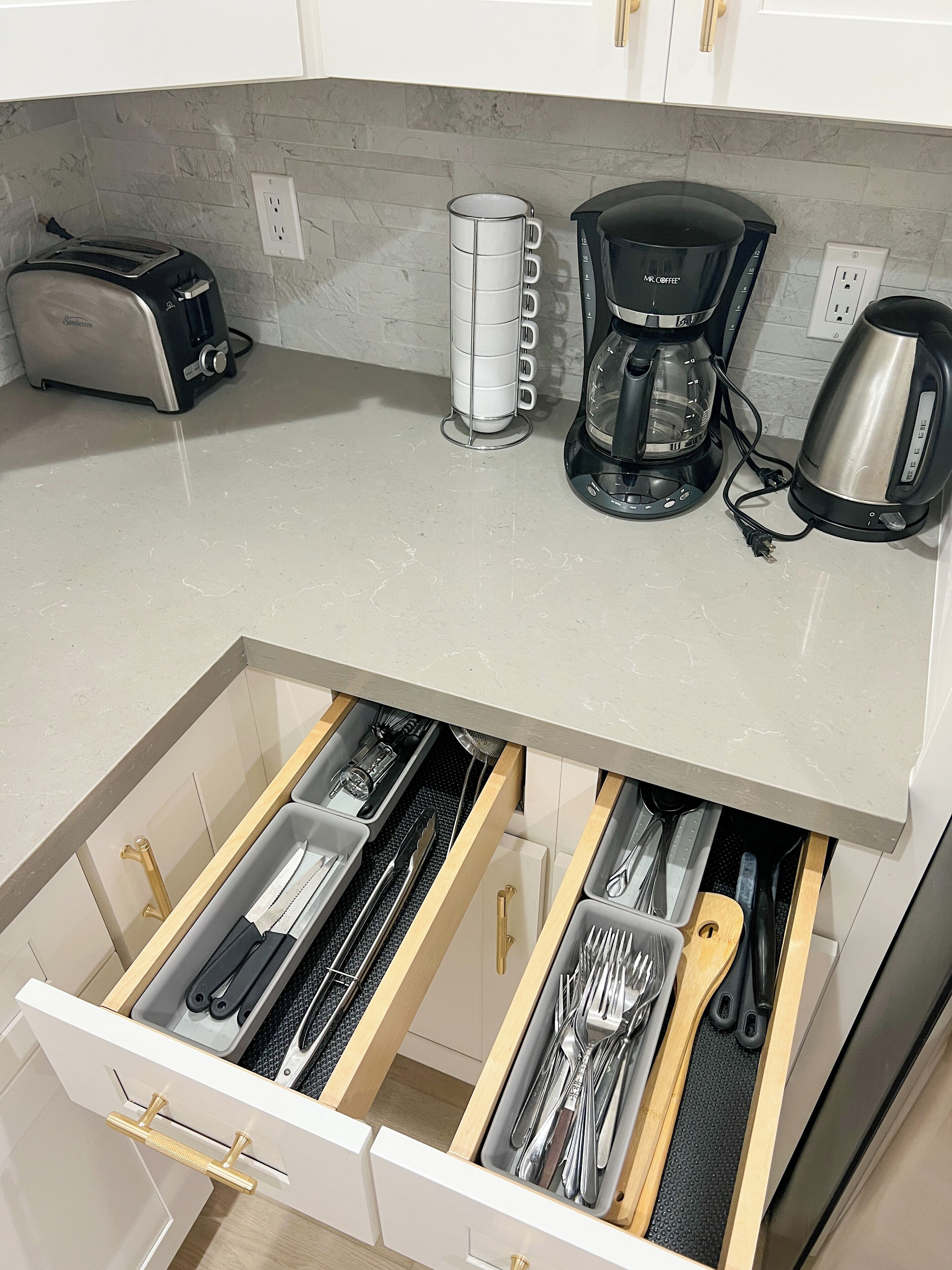 A kitchen with a toaster, a coffee maker, and a kettle on the counter.