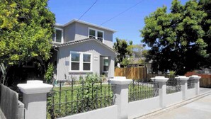 Une maison à deux étages avec un jardin devant, une clôture en bois et une allée pavée.