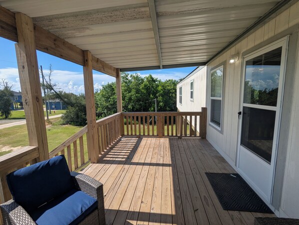 Une terrasse en bois couverte, dotée d’un siège intégré et d’une fenêtre.
