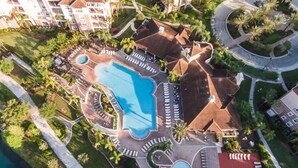 An aerial view of a resort with a central swimming pool, multiple buildings, and palm trees. - Deluxe 3 Bedroom Apartment Vista Cay Resort 404 (Orlando)