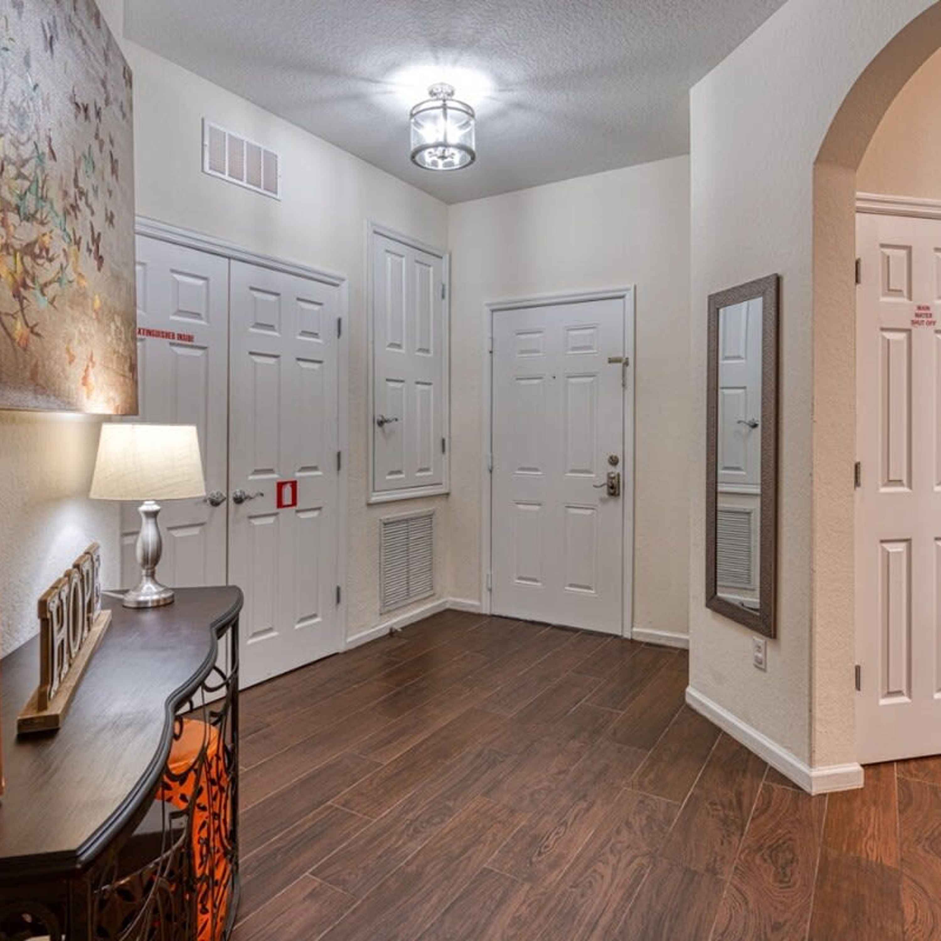 A hallway with wooden flooring, white doors, and a ceiling light fixture.