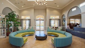 A spacious lobby with curved green sofas, a central coffee table, and large windows allowing natural light. - Deluxe 3 Bedroom Apartment Vista Cay Resort 404 (Orlando)