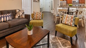 A living room with a sofa, two armchairs, a coffee table, and a dining area with chairs and a table. - Deluxe 3 Bedroom Apartment Vista Cay Resort 404 (Orlando)