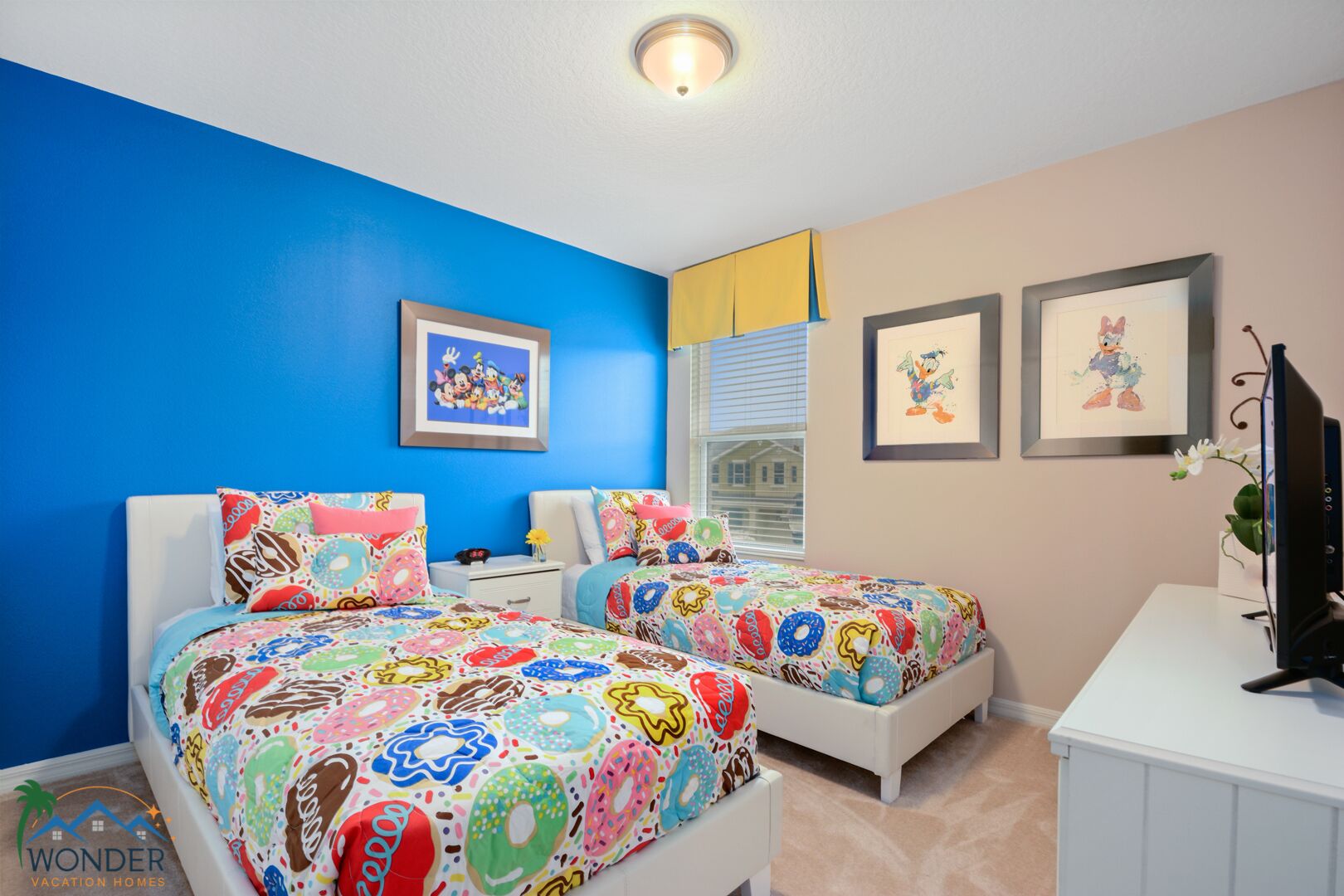A bedroom with two beds, a TV, and a window with blinds.