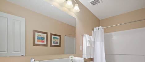 A bathroom with a sink, mirror, toilet, and shower.