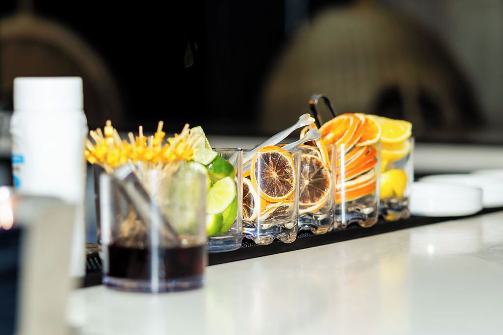 Een bar met een ruime selectie drankjes, waaronder cocktails met garnering en citruspartjes.
