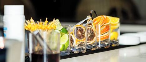 Een bar met een ruime selectie drankjes, waaronder cocktails met garnering en citruspartjes.