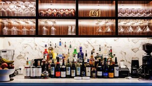 A bar area with shelves of wine glasses and bottles of liquor. - Angoria Hotel (San Angelo)