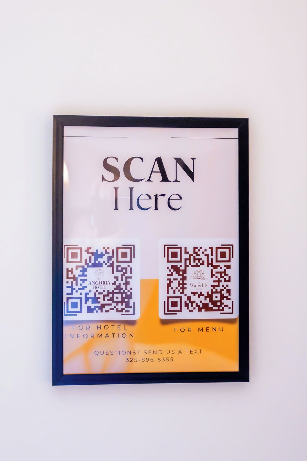 A framed sign with QR codes for hotel information and menu access, and a contact number for inquiries.