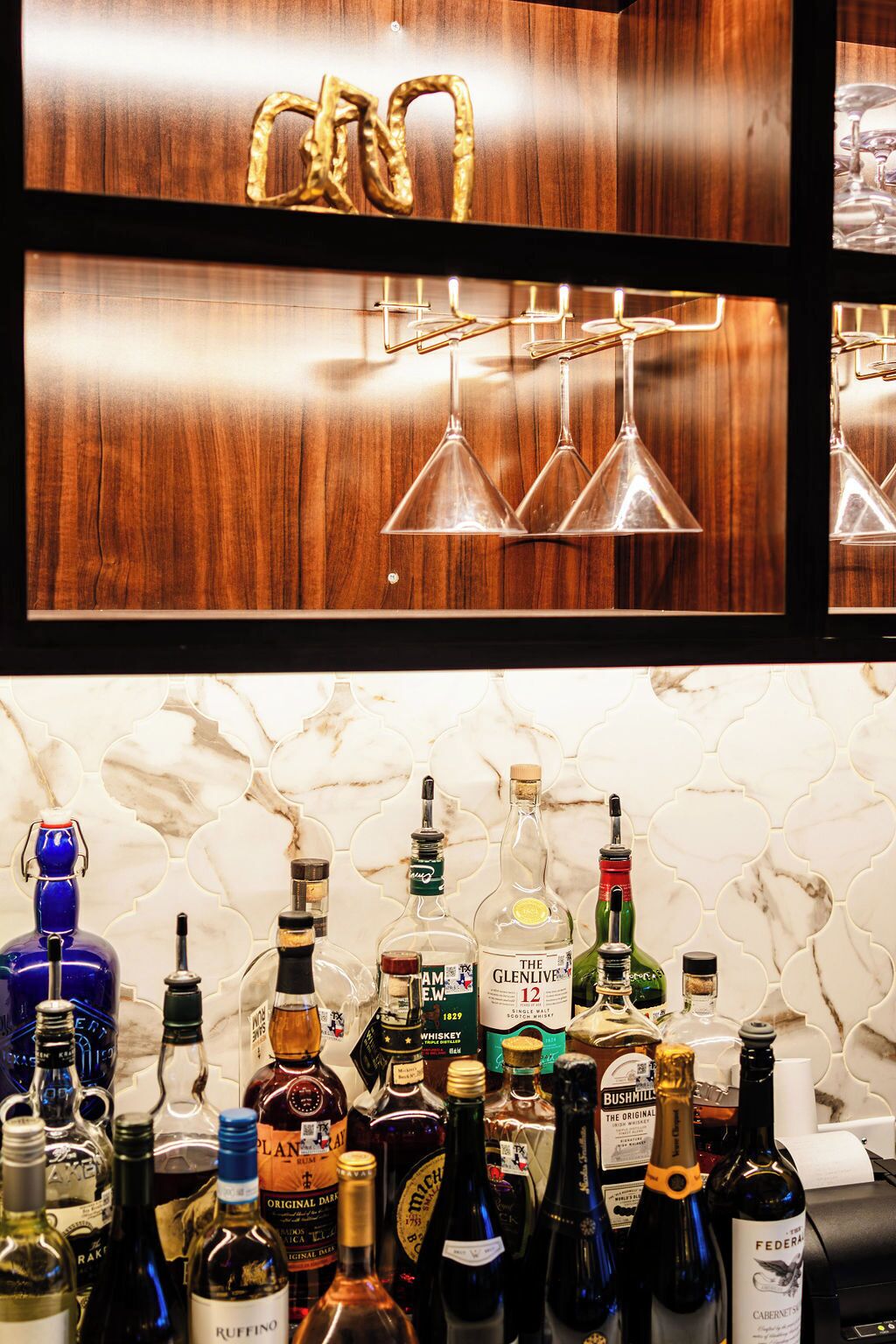 A bar area with a wooden backdrop and a variety of liquor bottles.