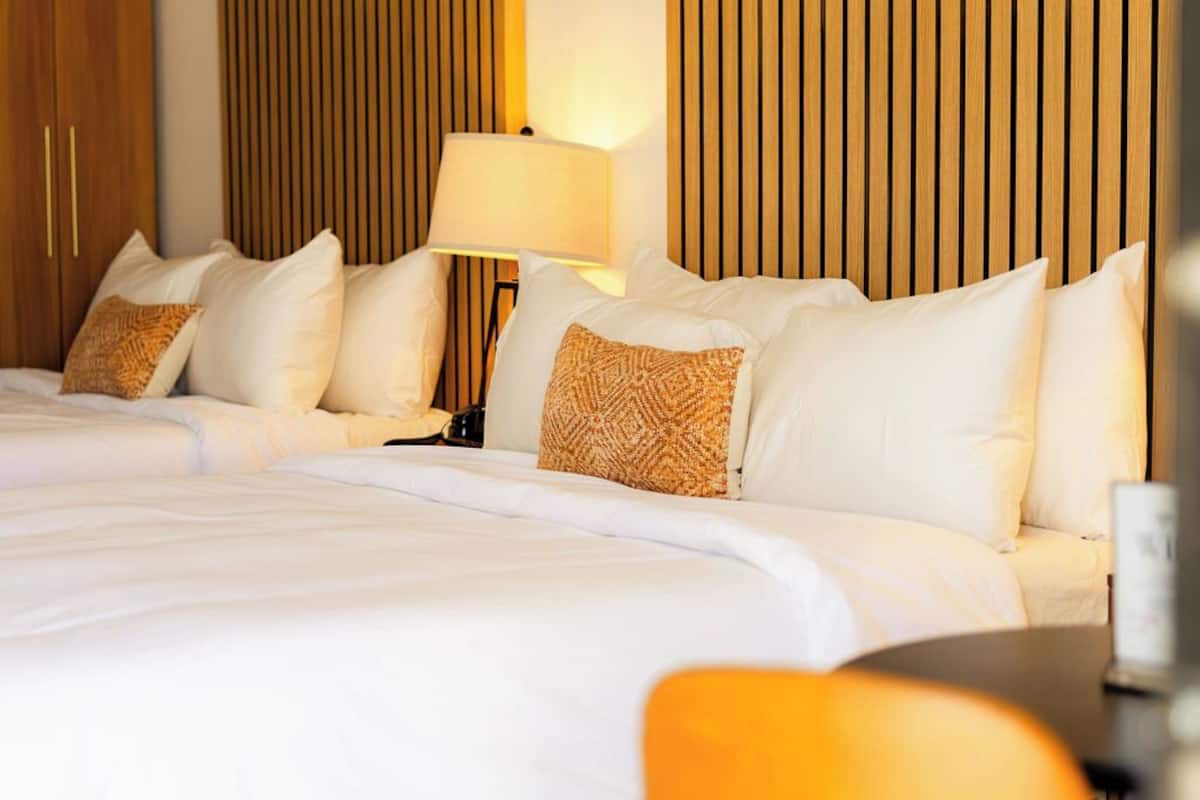 A hotel room with a large bed, a bedside table, and a lamp.