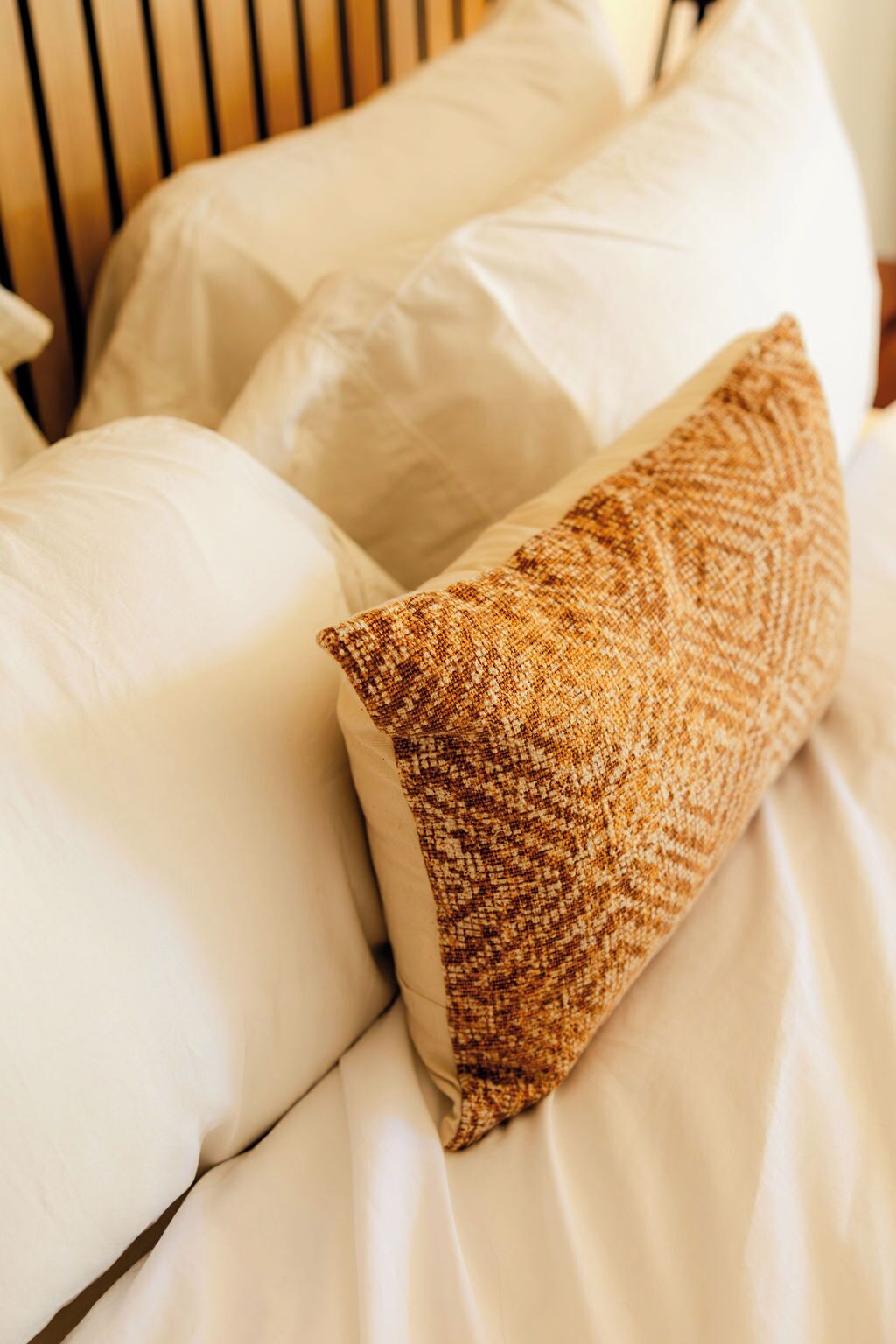 A bed with white and brown pillows.