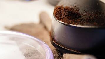 A close-up of a coffee grinder with a metal handle and a container of ground coffee.