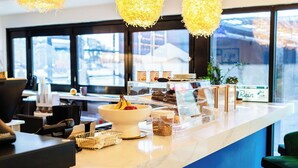 A modern café counter with a marble top, a bowl of fruit, and a display case with pastries. - Angoria Hotel (San Angelo)