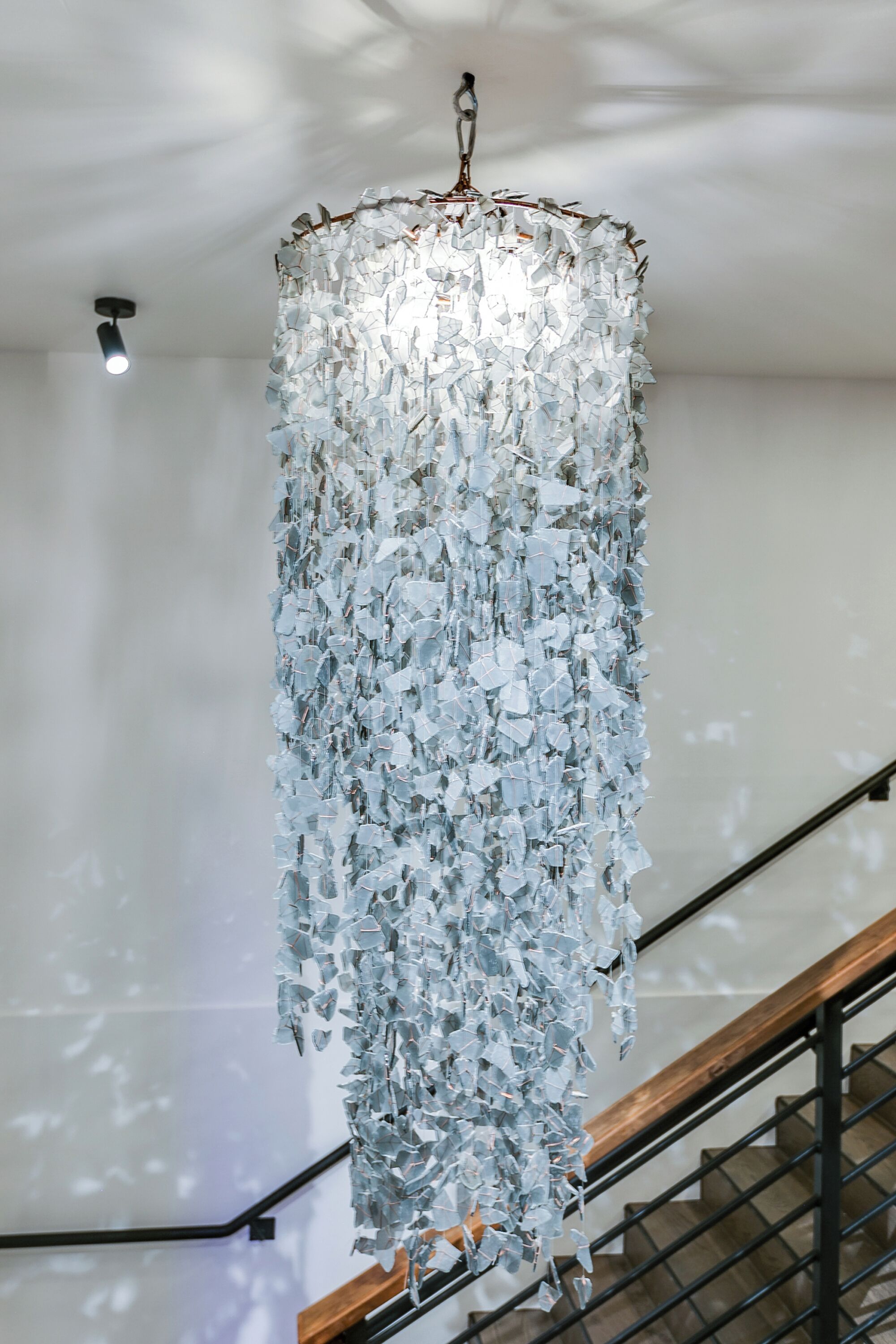 A chandelier made of numerous small, reflective elements hanging from a metal frame.