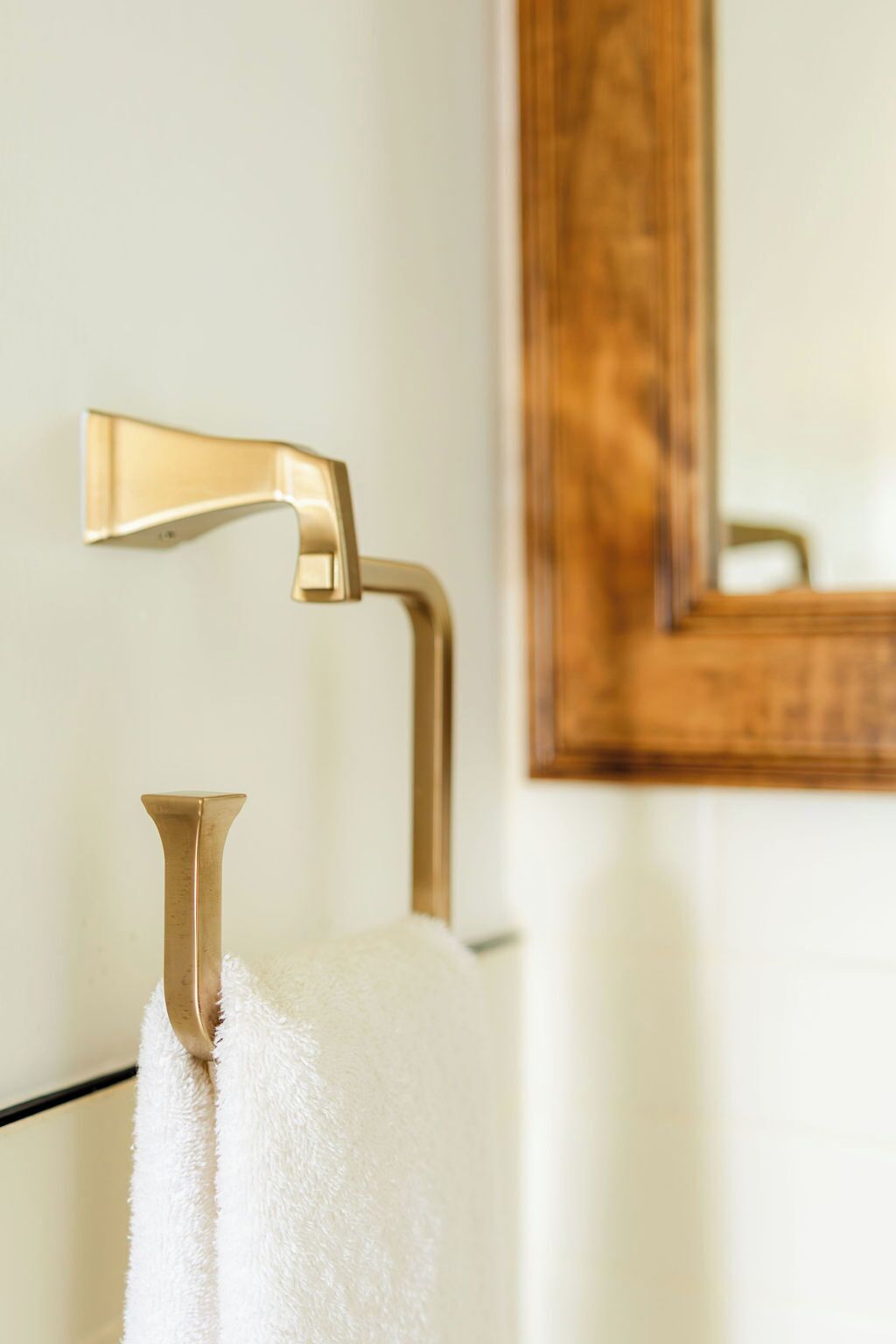 A bathroom with a gold towel rack and a mirror.